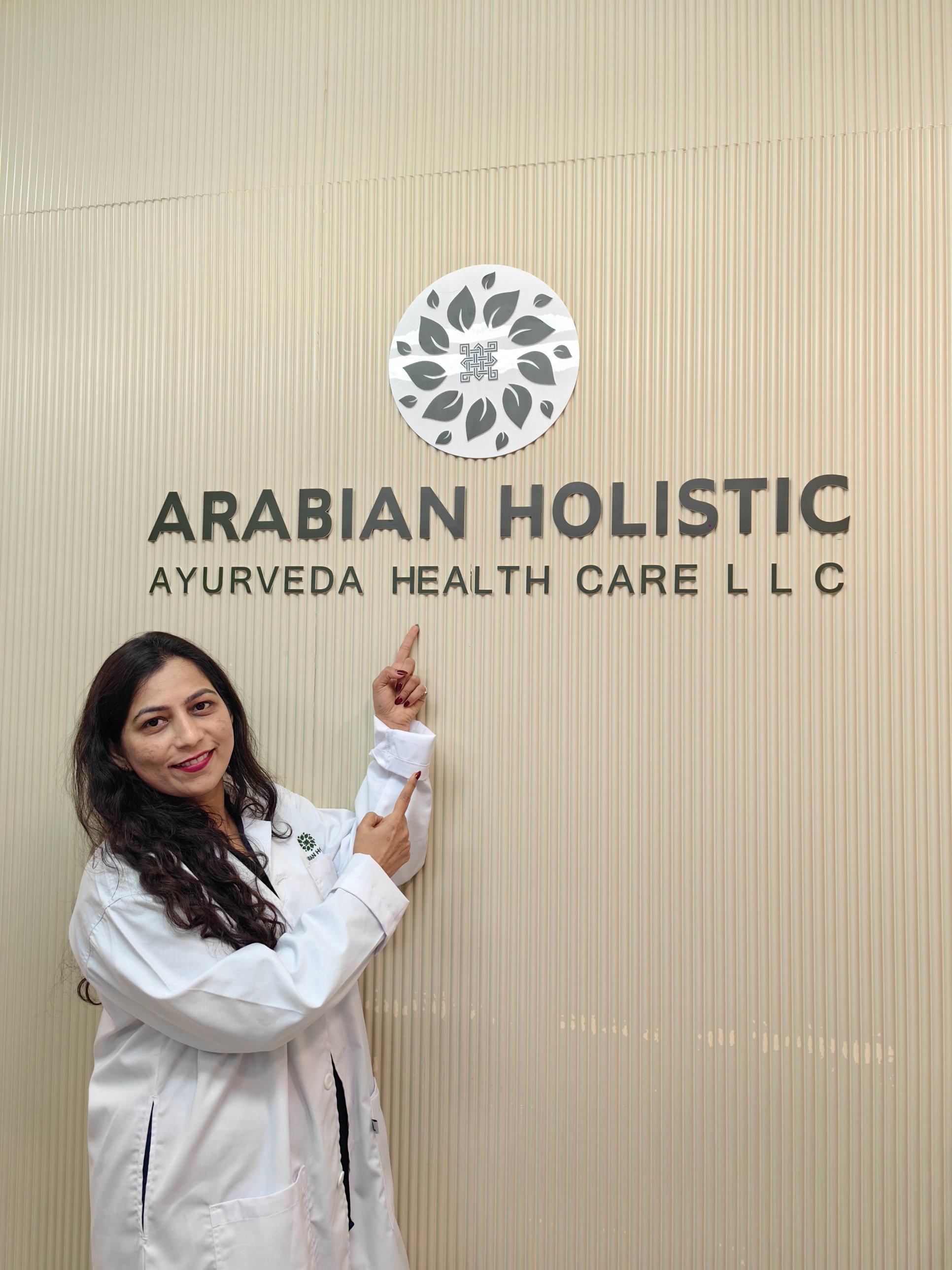 Reception wall with the Arabian Holistic Ayurveda Health Care logo and team member